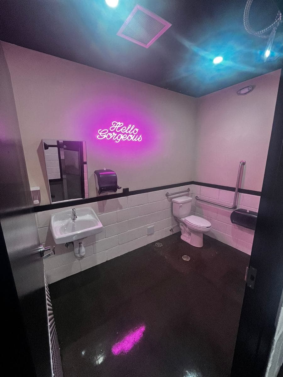 Bar washroom with a neon sign, clean sink and polished floor