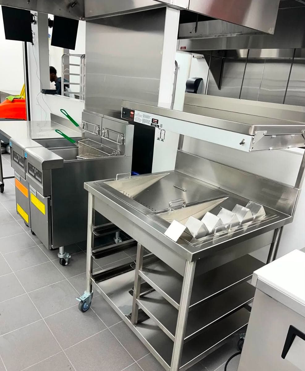 Stainless steel fryer station and prep tables in a commercial kitchen after cleaning