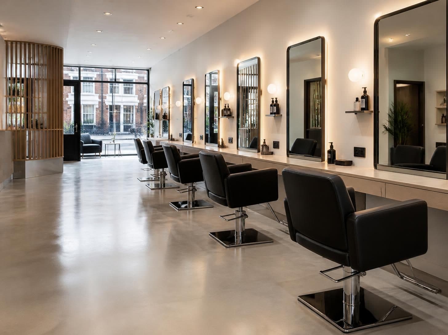 Row of styling stations with clean mirrors, black chairs and a polished floor in a London salon