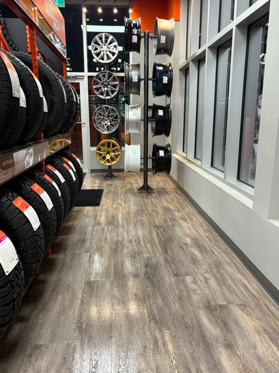 Showroom aisle with alloy wheels on display stands and a polished wood-effect floor