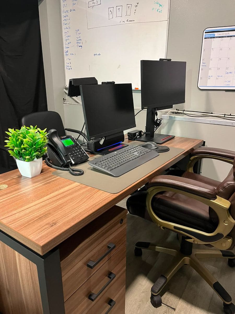 Office desk with twin monitors and a desk phone, wiped and tidied
