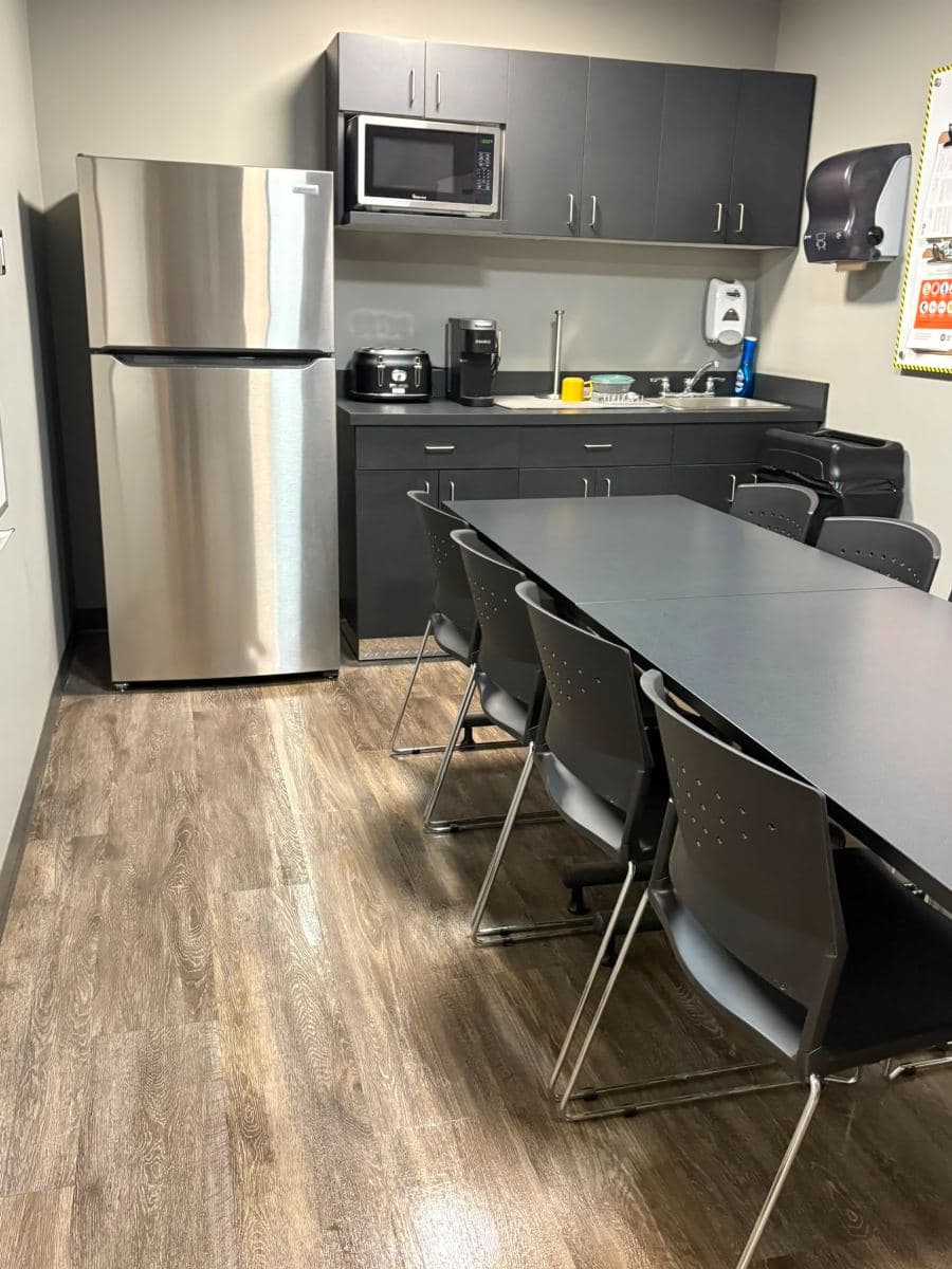Staff kitchen with a stainless steel fridge, clean worktops and a dining table